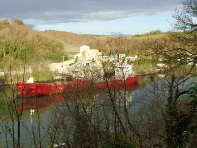 a red boat in the water in a river at Jordan Cottage in Fowey