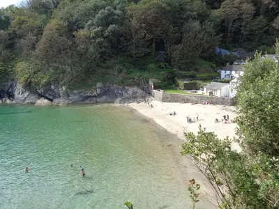 a beach with a group of people in the water at Jordan Cottage in Fowey