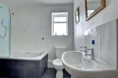 a bathroom with a tub and a toilet and a sink at Jordan Cottage in Fowey