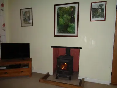 a living room with a fireplace and a tv at Jordan Cottage in Fowey