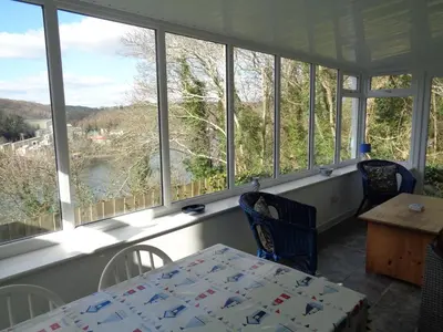 a room with a table and chairs and windows at Jordan Cottage in Fowey