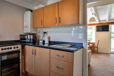 a kitchen with wooden cabinets and a black counter top at Finest Retreats - Cutkieve Farm Cottage in Middlehill