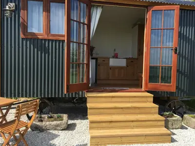 a house with a door and a table and a bench at Honeysuckle hut in Port Isaac
