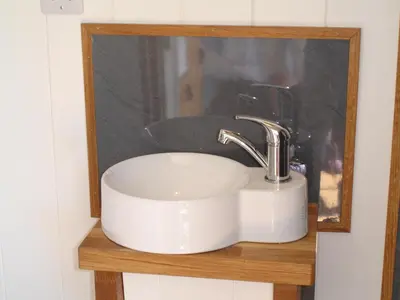 a white sink on a wooden shelf in a bathroom at Honeysuckle hut in Port Isaac