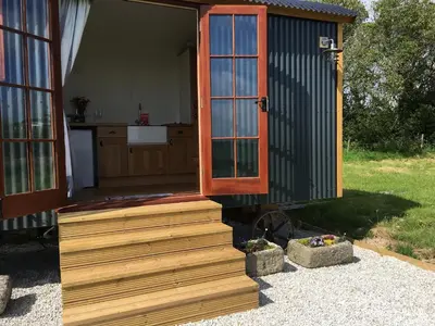 a tiny house with a porch and a kitchen at Honeysuckle hut in Port Isaac