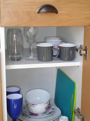 a cupboard filled with plates and bowls and glasses at Honeysuckle hut in Port Isaac