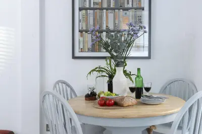 a table with a vase of flowers and fruit on it at May Cottage in St Ives