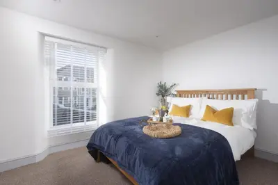 a bedroom with a bed with a blue blanket and a window at May Cottage in St Ives