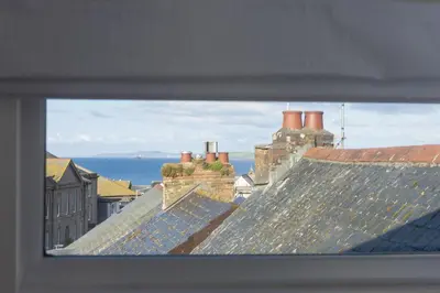 a view of roofs of buildings with the ocean in the background at May Cottage in St Ives