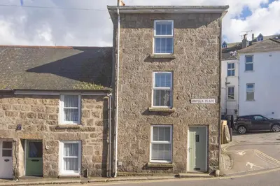 an old stone house on the corner of a street at May Cottage in St Ives