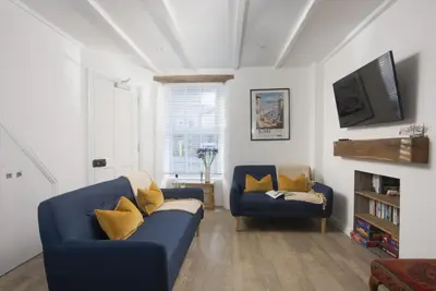 a living room with two blue couches and a tv at May Cottage in St Ives