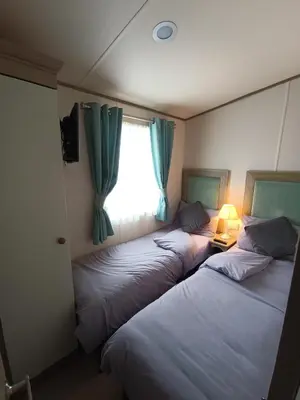 two beds in a room with a window and a lamp at 16 Lakeview, Pelham Retreat in Crantock