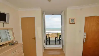 a room with a door to a balcony with a view of the ocean at Beach View House - Self Catering Hayle, St Ives Bay Cornwall in Hayle