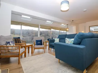 a living room with a blue couch and chairs at Anjoma in Looe