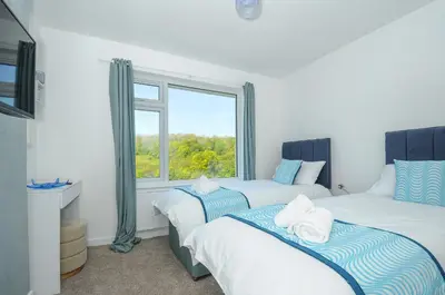 two beds in a room with a window at Anjoma in Looe