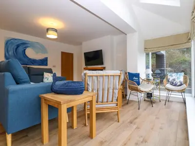 a living room with a blue couch and a table at Anjoma in Looe