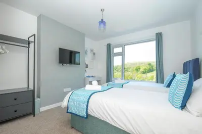 a bedroom with a large bed and a window at Anjoma in Looe