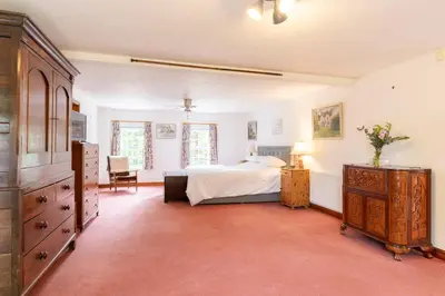 a bedroom with a bed and a dresser and a table at Lolgorien, West Cornwall, Sleeps 8 in Camborne