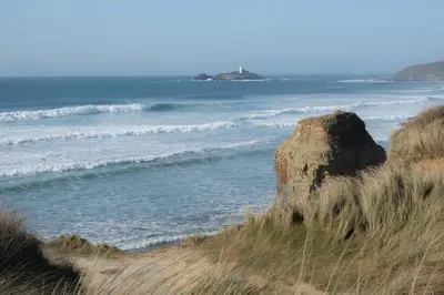 a beach with a large rock and the ocean at Lolgorien, West Cornwall, Sleeps 8 in Camborne