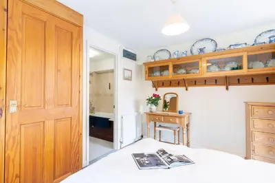 a room with a bed and a wooden cabinet and a door at Lolgorien, West Cornwall, Sleeps 8 in Camborne