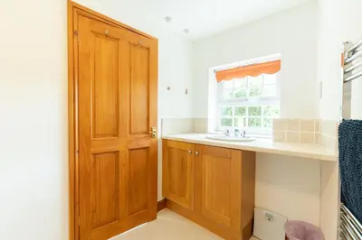 a bathroom with a sink and a wooden door at Lolgorien, West Cornwall, Sleeps 8 in Camborne