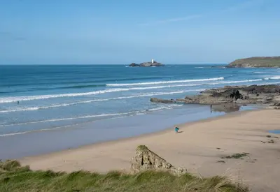 a person standing on a beach with the ocean at Lolgorien, West Cornwall, Sleeps 8 in Camborne