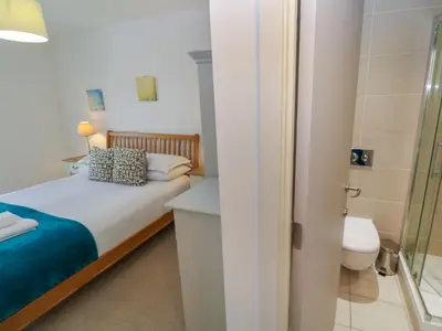 a bedroom with a bed and a shower and a toilet at Talland View in St Ives