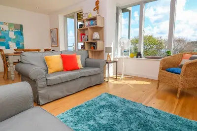 a living room with a gray couch and a blue rug at Talland View in St Ives