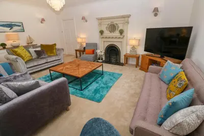 a living room with couches and a tv and a fireplace at Hindon Hall in St Ives