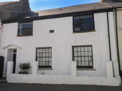 a white house with black windows at Carew House Cottage in Redruth