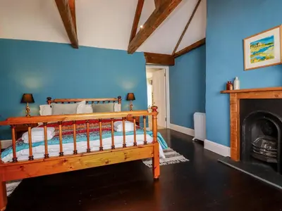 a bedroom with blue walls and a wooden bed at Carew House Cottage in Redruth