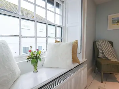 a window seat with a vase of flowers on it at Carew House Cottage in Redruth