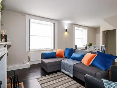 a living room with a couch with blue and orange pillows at Carew House Cottage in Redruth