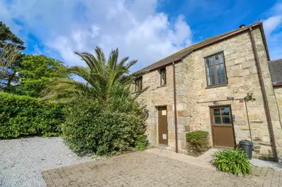 an old stone house with a palm tree in front of it at The Granary in Penzance