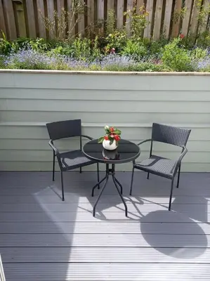 two chairs and a table with a vase of flowers on a patio at Rose's Cottage in Gorran Haven