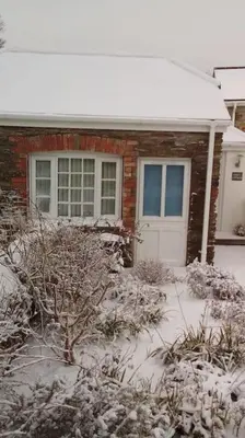 a house with a snow covered front yard with a white door at Rose's Cottage in Gorran Haven