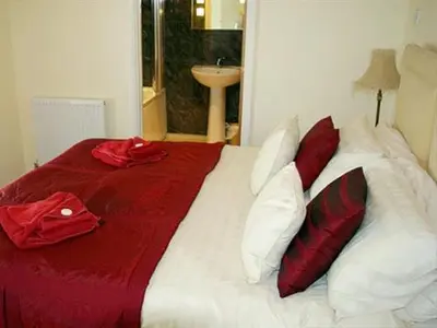 a bed with red and white pillows on it at Porth Lodge in Newquay