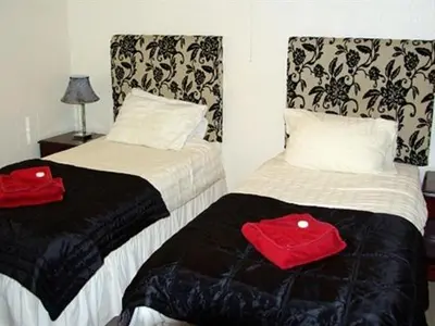 two beds in a room with red towels on them at Porth Lodge in Newquay