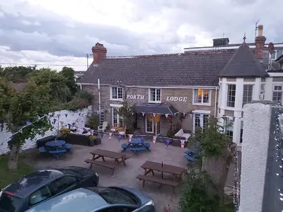 a pub with picnic tables in front of a building at Porth Lodge in Newquay