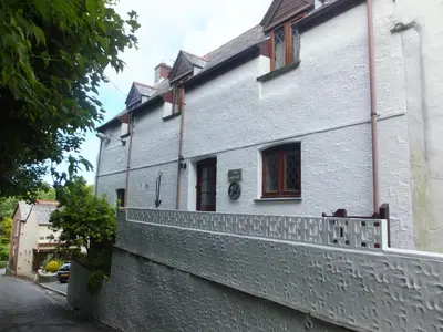 a white building with a fence on the side of it at Cosy holiday cottage in Boscastle in Boscastle