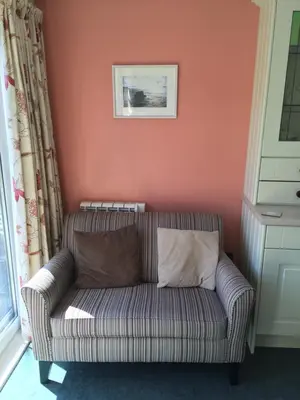 a living room with a couch against a pink wall at Cosy holiday cottage in Boscastle in Boscastle