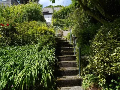 a set of stone stairs in a garden with plants at Cosy holiday cottage in Boscastle in Boscastle