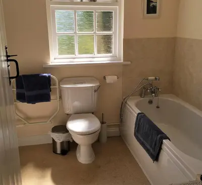 a bathroom with a toilet and a tub and a window at Cosy holiday cottage in Boscastle in Boscastle