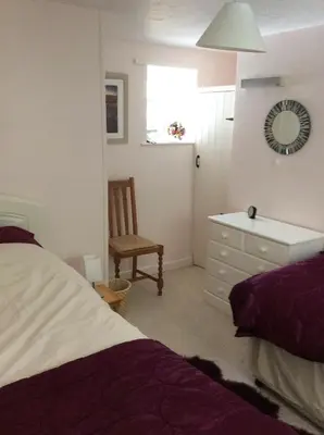 a bedroom with a bed and a chair and a dresser at Cosy holiday cottage in Boscastle in Boscastle