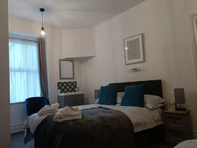 a bedroom with a large bed with blue pillows at Tregella Guest House in Newquay