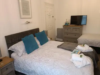 a bedroom with a bed with blue pillows and a television at Tregella Guest House in Newquay