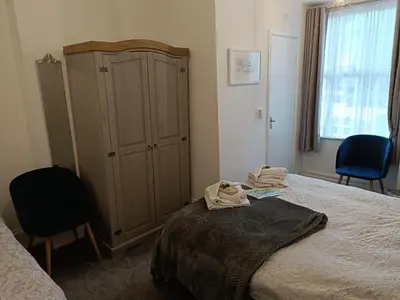 a bedroom with a bed and a cabinet and two chairs at Tregella Guest House in Newquay