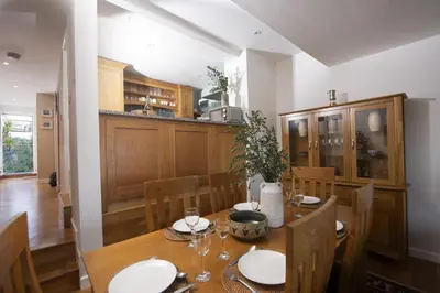 a dining room with a table and a kitchen at 4 Glendorgal Sands, Newquay in Newquay
