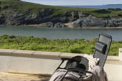 a bench sitting on a ledge overlooking a beach at 4 Glendorgal Sands, Newquay in Newquay