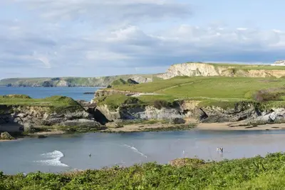a body of water with a beach and cliffs at 4 Glendorgal Sands, Newquay in Newquay